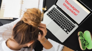 Mulher triste, desanimada em frente ao computador. Mensagem bloqueada.